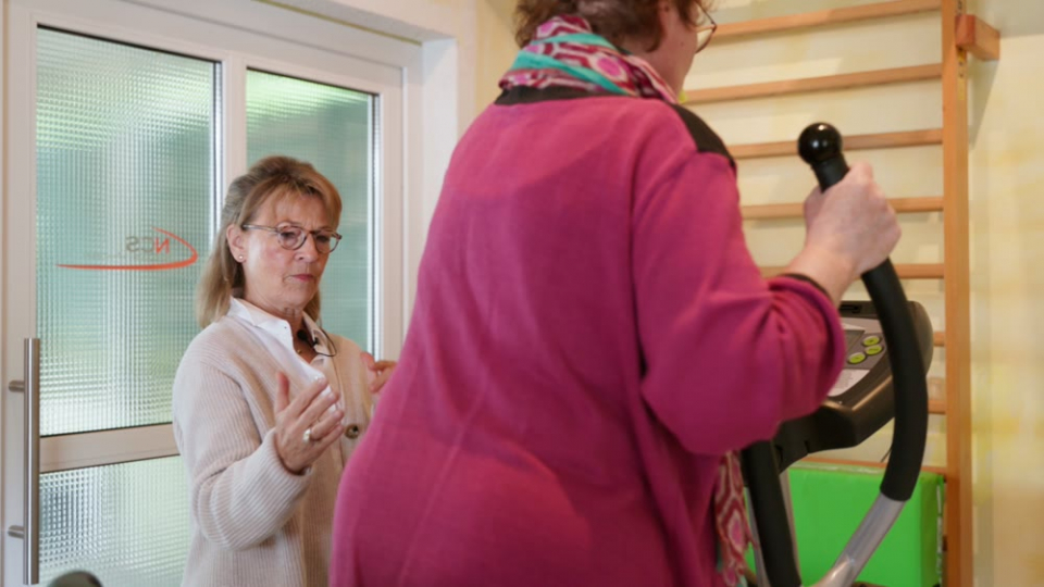 isst stellenangebot therapie Therapeutin begleitet eine Patientin beim Training am Gerät